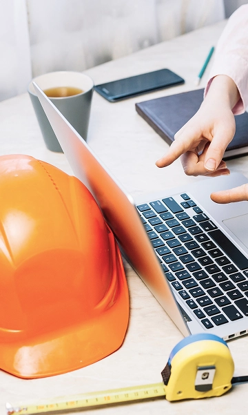 Construction helmet next to a laptop and documents during technical system review.