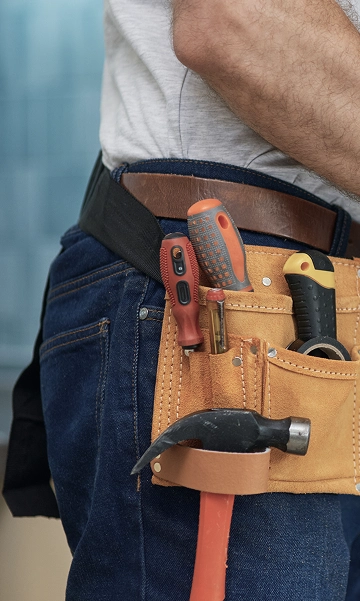 Close-up of a maintenance worker’s tool belt equipped with screwdrivers and pliers.