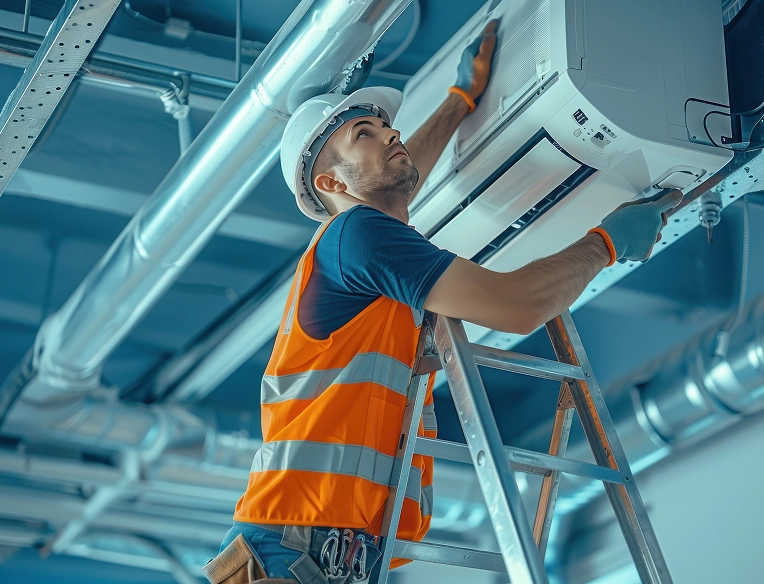 HVAC technician on ladder inspecting air conditioning unit in commercial ceiling space