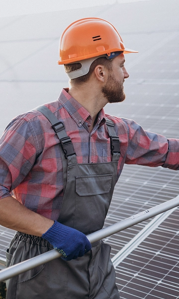 Worker in safety gear looking upward during exterior maintenance of a facility.