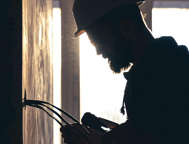 Silhouetted technician working on electrical wiring in low light environment